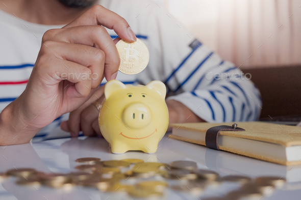 Man\'s hand putting coin money in yellow pig bank for future wealth.Piggy bank placed on desk