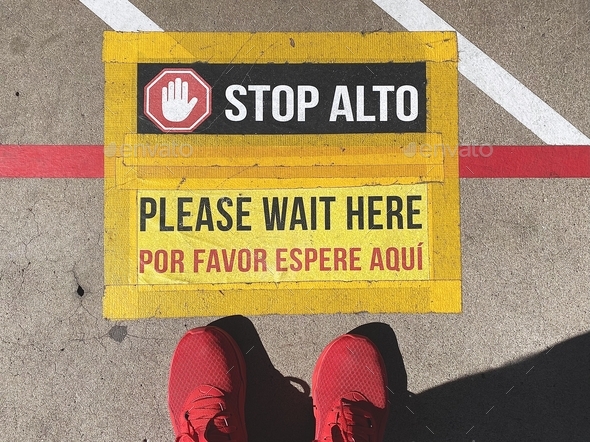 Social distancing sign asking people to stop and wait so you don’t get too close to the next person
