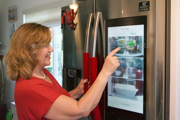 Woman using modern technology built into her refrigerator to find food without opening the door!