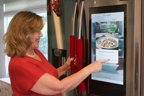Woman using modern technology built into her refrigerator to find recipes for dinner!
