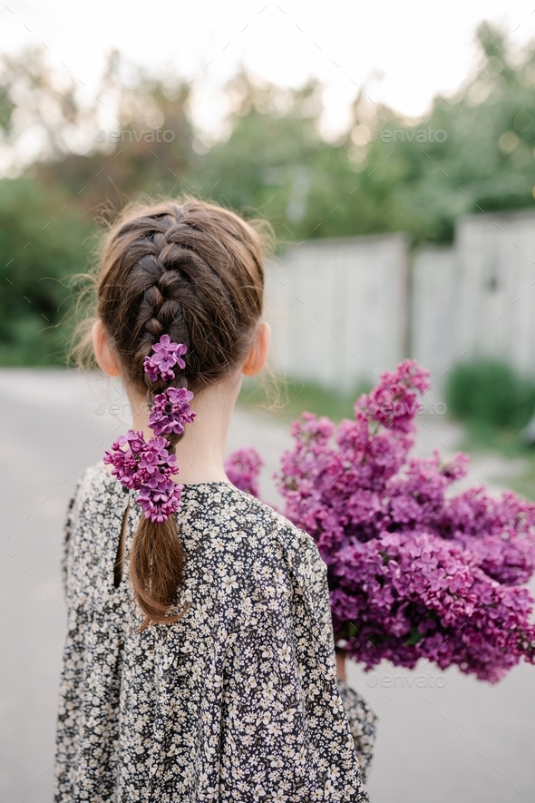 Cute little girl wearing dress holds a large bouquet of lilacs flowers. Spring concept - Stock Photo - Images