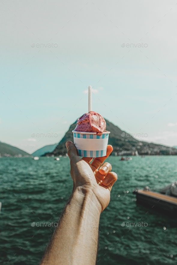 Close-up of hand holding Ice Cream cup against lake landscape - Stock Photo - Images