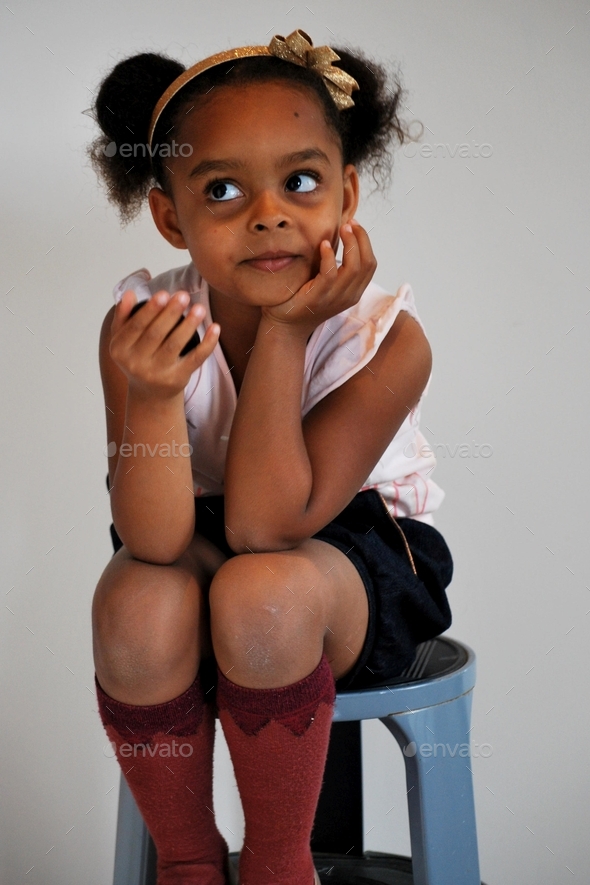 Cute girl (black /mixed) wearing a hair bow and posing with cute knee socks - smile rolling eyes