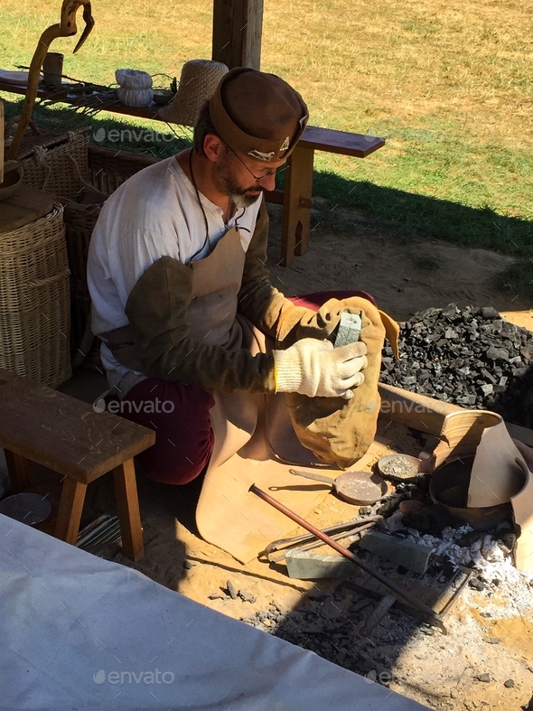 Medieval blacksmith working on metal object - history reenactment
