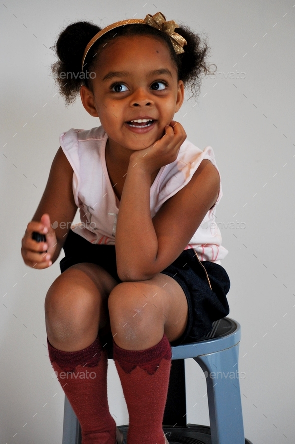 Cute little girl (black /mixed) wearing a hair bow and posing with cute knee socks - smile