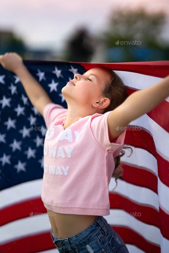 Beautiful caucasian girl standing with the American Flag. Freedom