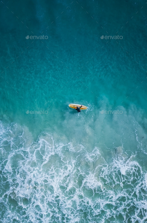 Surfer in blue ocean from above