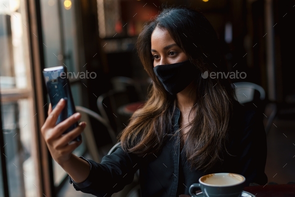 Young woman on video call with face mask
