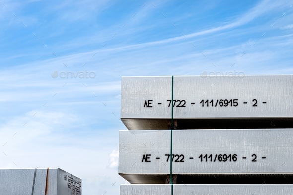 Heavy aluminum bars stacked on top of each other in an aluminum smelting plant, against the blue sky