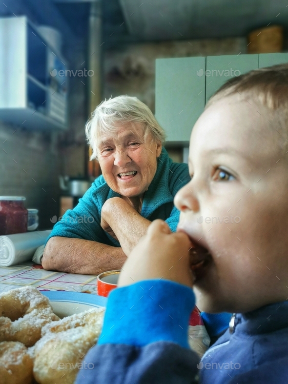 Great-grandmother watches her grandson eat
