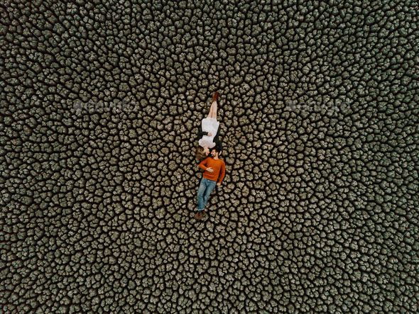 Earth love. Bird eye view of a couple laying on the ground of a dry lake with cracked earth pattern
