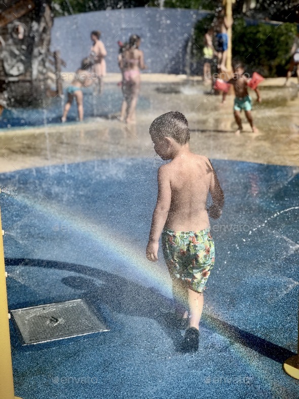 Little boy walking across water splashes