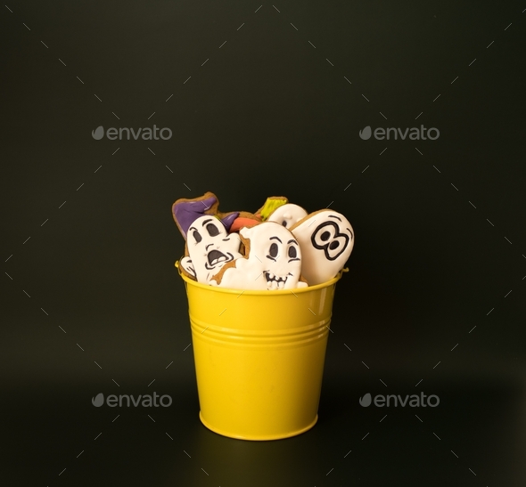 A bucket filled with gingerbreads in the form of ghosts and pumpkins. Sweet gifts for Halloween