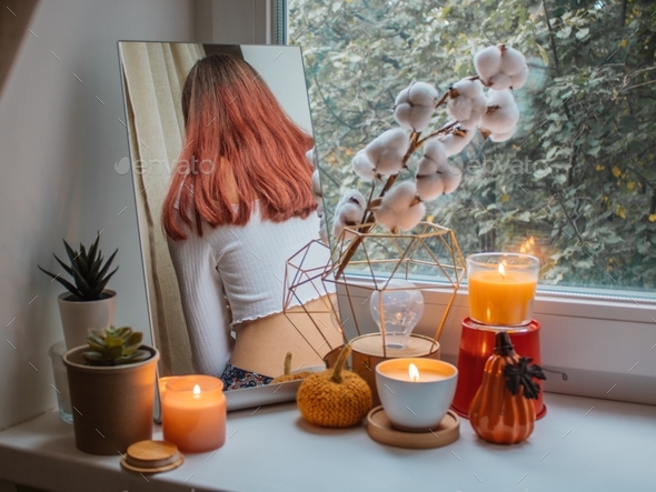 Girl with red hair sits in her room on a window sill decorated for the holiday.