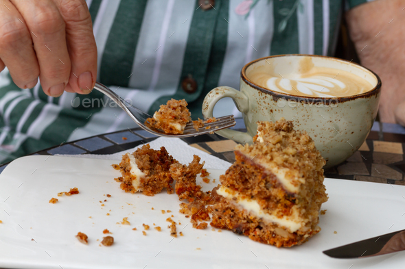 A piece of carrot cake on a saucer in a cafe.next to the fork eating outside concept.