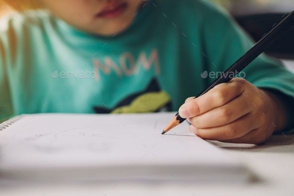 Little cute girl doing homework by writing alphabet with pencil. Concept for learning and education