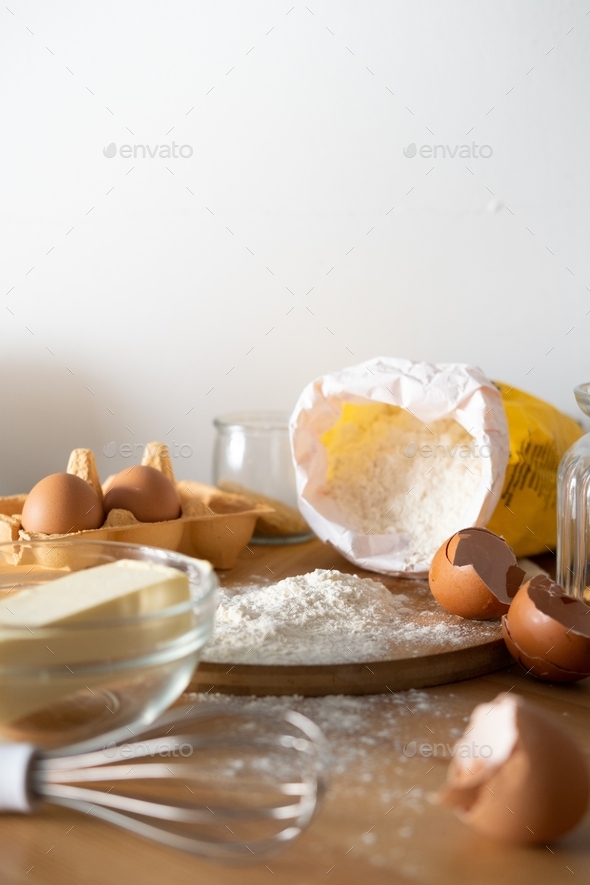 Baking cake or cupcakes ingredients - butter, flour, whisk, eggs and eggshells on wooden chalkboard