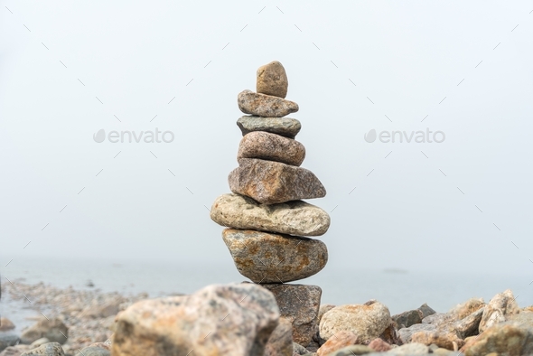 Stack of stones cairn on foggy beach - Stock Photo - Images