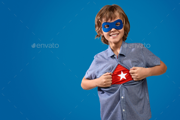 Cheerful boy showing superhero costume