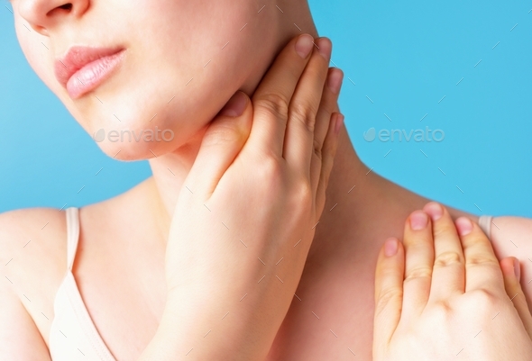 Female hands do self-massage of the face close-up on blue background.