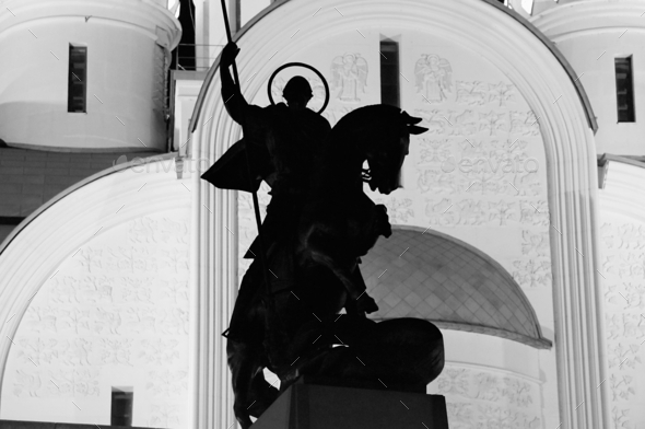 Silhouette of the monument to St. George the Victorious against the background of a large temple