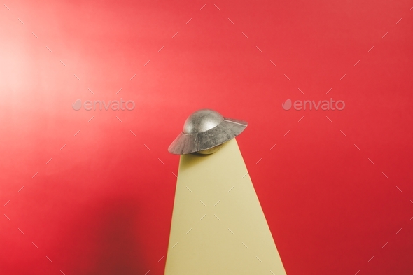 UFO and tractor beam with a red background