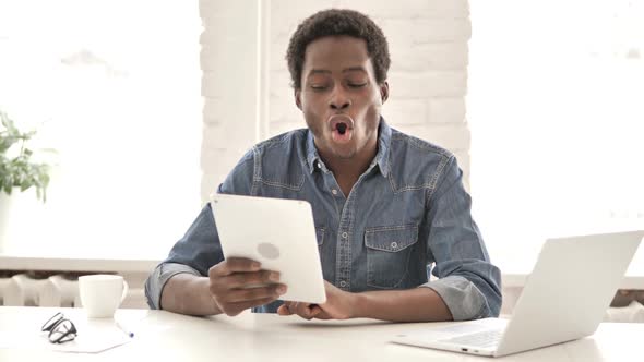 African Man Celebrating Success While Using Tablet alt