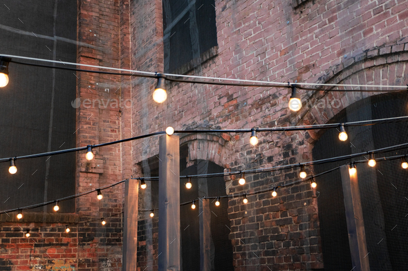 An empty courtyard lit by garlands of warm light bulbs