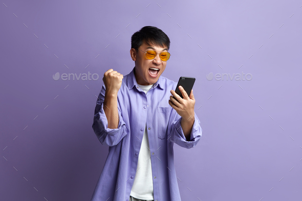 Winner Man Rejoicing Smartphone. Extremely Happy Asian Guy Raised Arm Gesturing