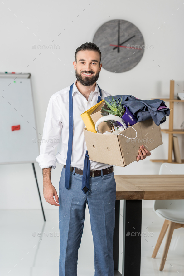 portrait of smiling businessman with cardboard box in hands quitting job