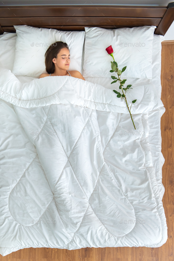 The woman sleeping with a rose on the bed. view from above Stock Photo