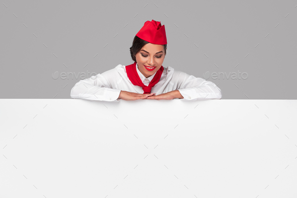 Happy stewardess looking at advertisement poster