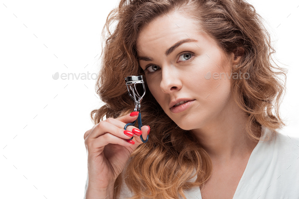 Beautiful young woman holding curling tongs and looking at camera isolated on white