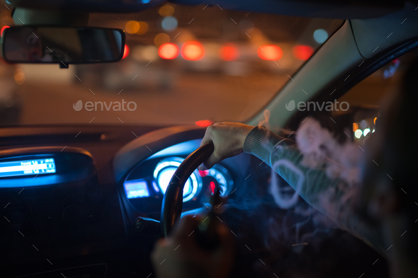 The man make a smoke rings in the car. Evening night time