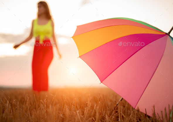 Colorful umbrella in field near woman
