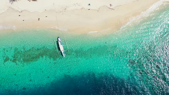 Jukung boat anchoring on tranquil shoreline of tropical island with white sandy beach washed by turq alt