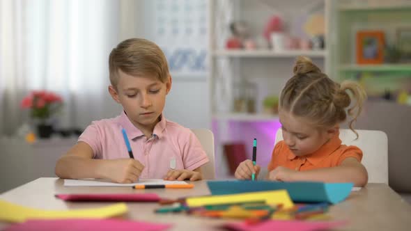 Adorable Boy and Girl Drawing by Pencils Sitting at Table, Kindergarten Leisure alt