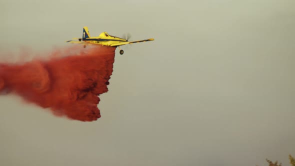 Fire fighter plane drops fire retardant on a forest fire in the hills alt