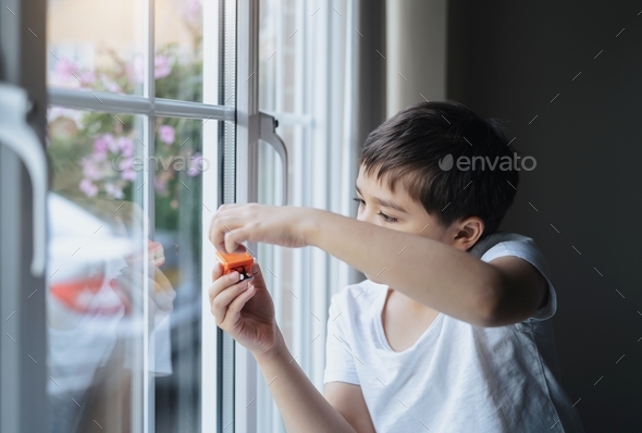 Kid playing with toy and looking at the midge climbing up outside of double glazed window.