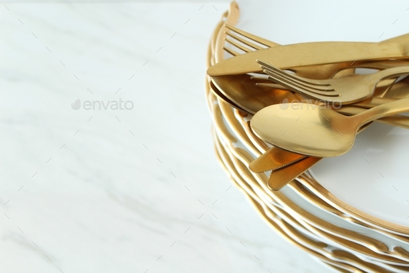 Elegant white and gold dishes and cutlery frame copy space