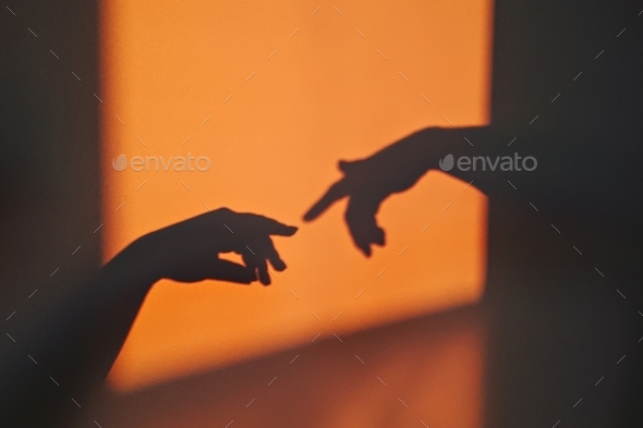 Silhouette of gesture touch by humans palms from sunbeam on wall during posing wrist and fingers