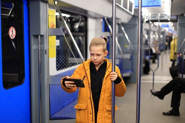A boy in a yellow jacket is alone in public transport. teenager on the subway in mobile phone