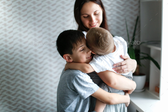 older brother hugs mom and baby in arms of mom, concept siblings ...