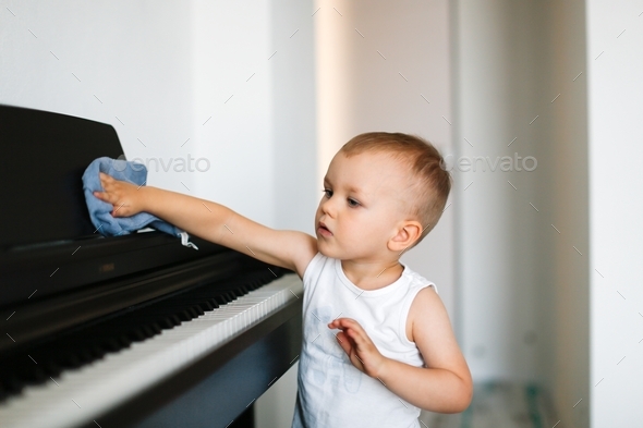 cute kid toddler dusting the piano, toddler helping to clean the house, care and helping mom