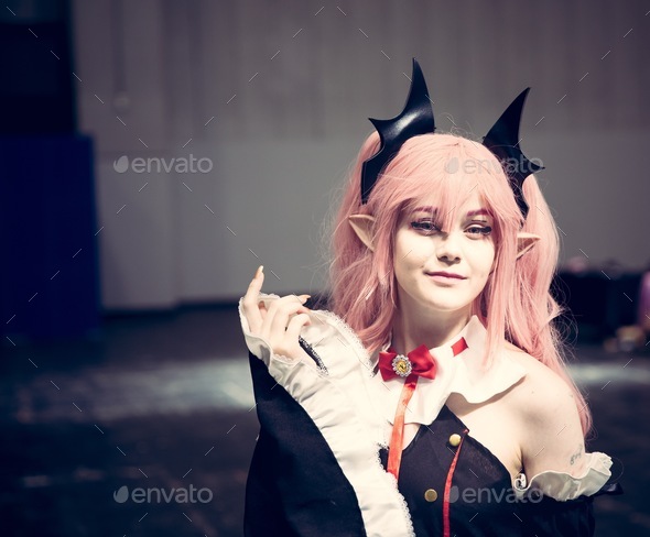 A pretty cosplay girl as Japanese Anime character with pink hair and bat ears at at comic con event