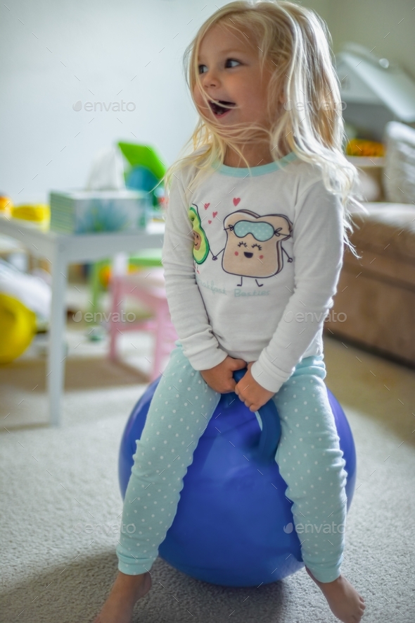 Happy Little girl playing on bouncy ball in pajamas