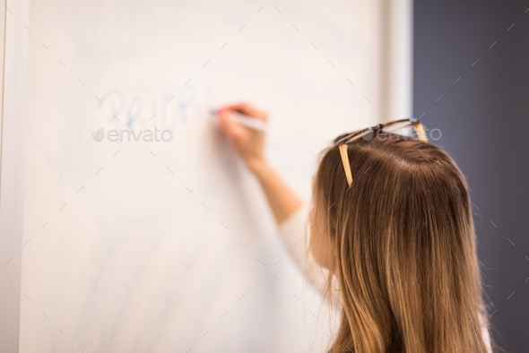 Project manager writing priorities on whiteboard in business meeting