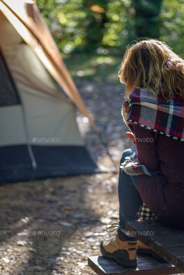 Woman sitting on picnic bench on fall morning outside tent