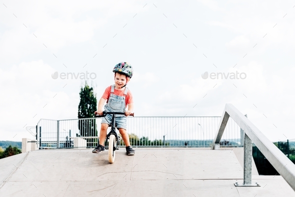 Boy in colorful helmet riding a balance bike, going down the ramp Stock ...