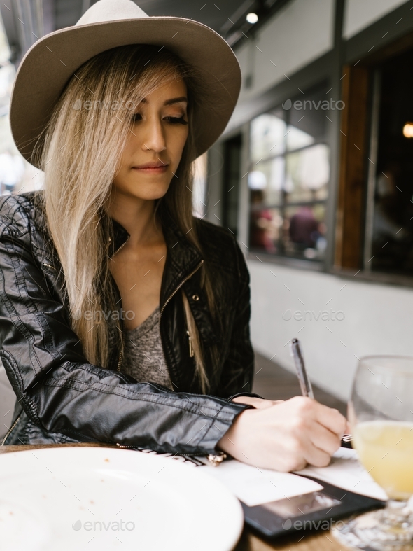 Young trendy hipster woman dining out restaurant signing check bill hat millennial paying credit
